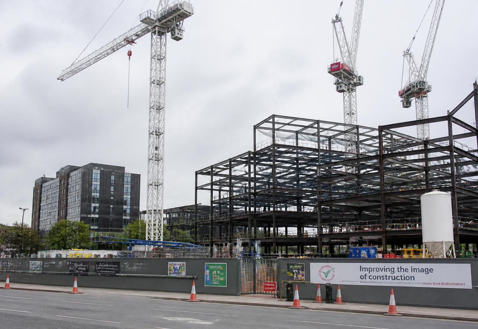 Major UK construction project with tower cranes, steel frame and site hoarding